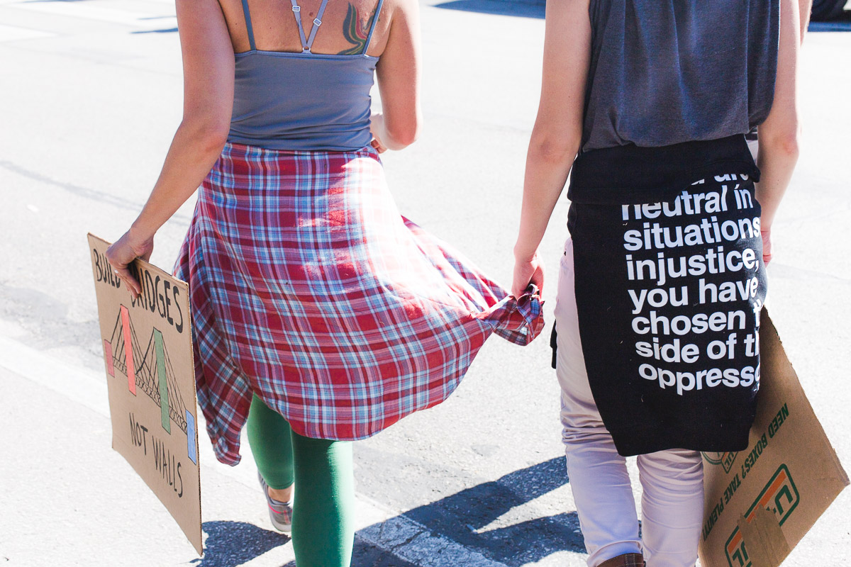 younger sister holding older sister's long shirt sleeve while walking