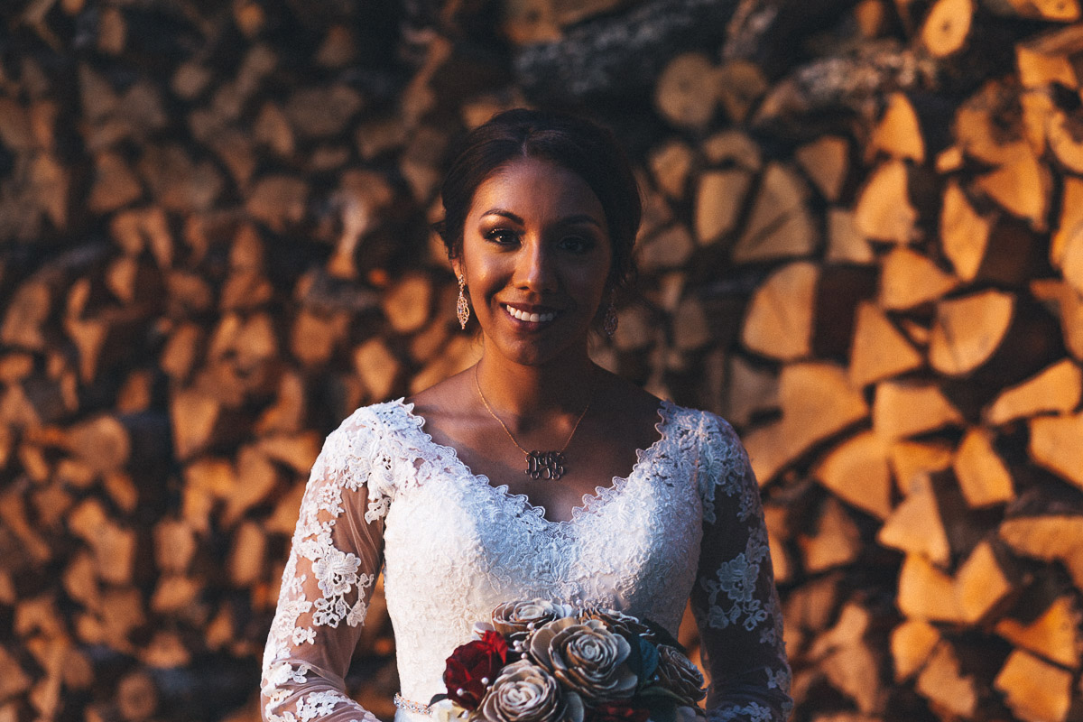 dramatic lighting shadows bride in front of firewood stack